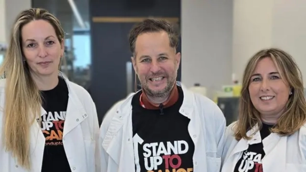 Зліва направо: професор Петра Гамерлік, Алекс та Емма Дейвіс у лабораторії Манчестерського центру дослідження раку. Всі в білих халатах та з посмішками.