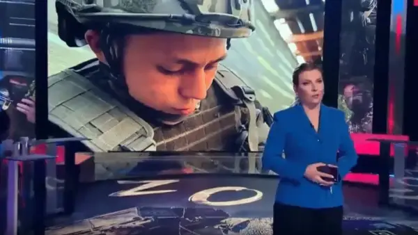 Російський військовослужбовець в уніформі заряджає кулеметну стрічку.