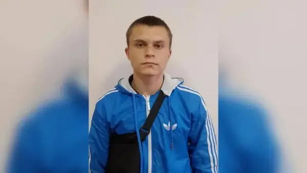 Молодий чоловік у військовій формі, ймовірно російській, із символікою підрозділу, що стоїть на тлі військової техніки 4